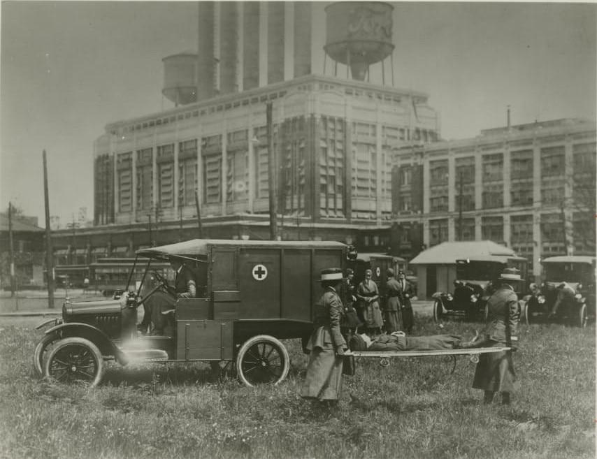 The American Red Cross carries out training with the help of a Model T in front of the Highland Park Plant.